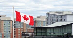 Canadian flag waving over urban city buildings